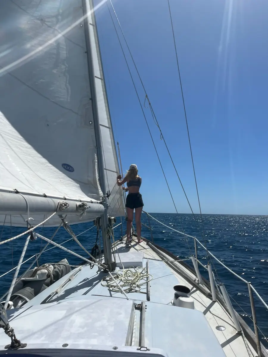 Standing at the bow of a sailing yacht under sail on open blue water