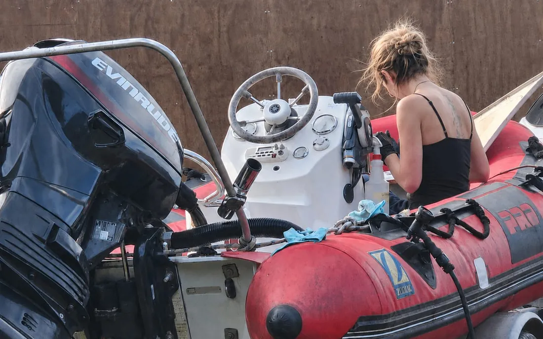 Cleaning the console and tube of a red RIB on its trailer