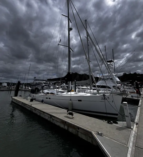 A cruising yacht moored at a marina pontoon under a dramatic cloudy sky