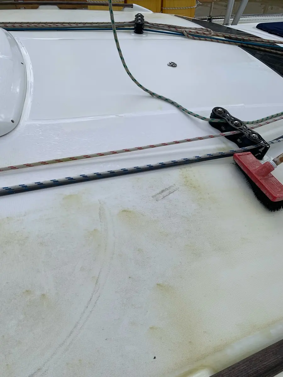 A white fibreglass deck, clean at the top and yellow-stained below, with a scrub brush resting on it