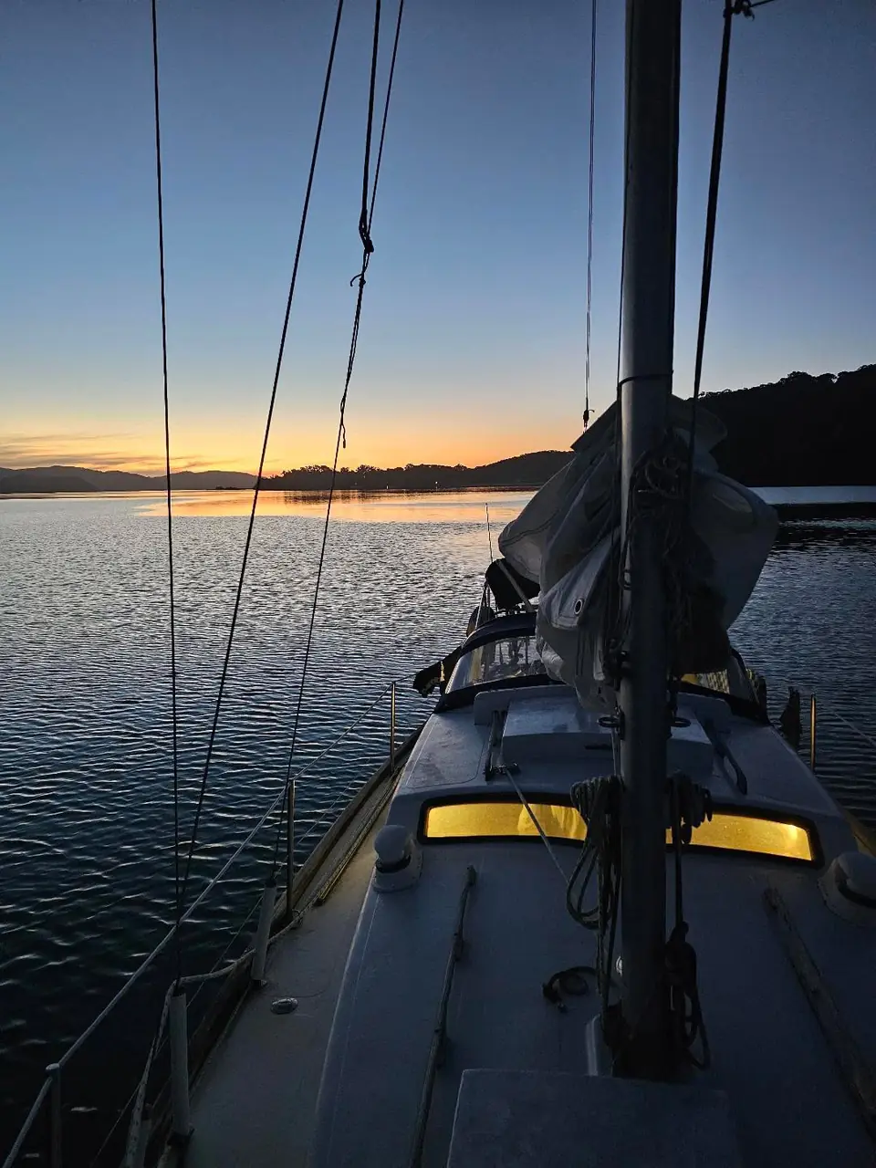 Looking along the deck of a sailing boat at dusk, with the last light over the water